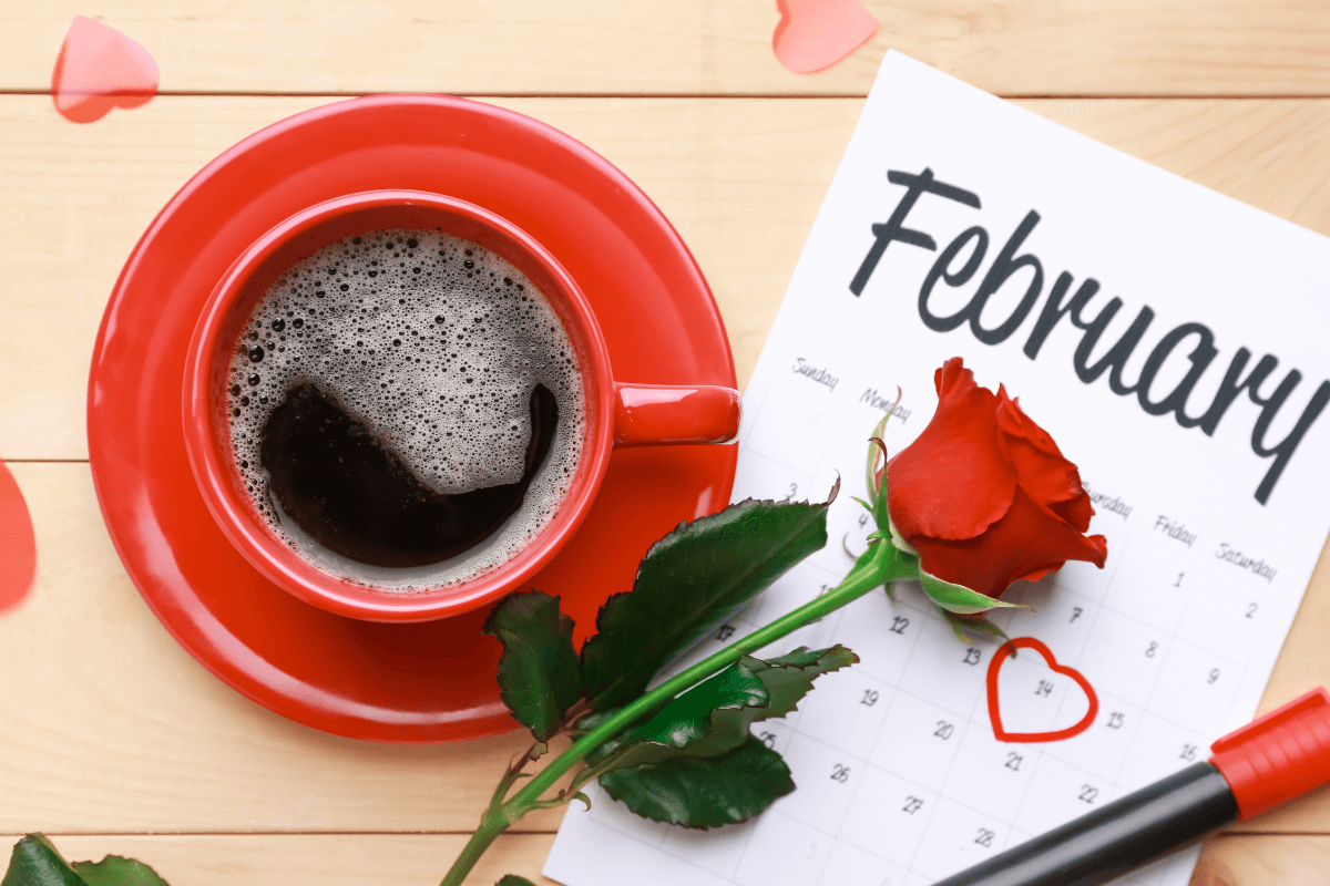 Image of calendar showing the month of February covered by a rose and a red coffee mug of to the left side