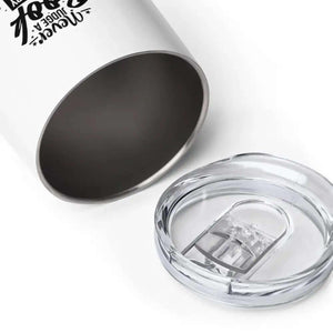 The 12 oz Never Judge A Book Wine Tumbler, Travel Tumbler features double-wall vacuum-sealed stainless steel and comes with a clear plastic lid, shown beside it on a white surface.