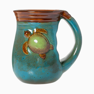 The 18oz Stoneware Handwarmer Mug, Turtle, features a blue and brown glaze with a raised green sea turtle design on the side.