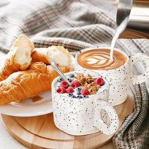 Two croissants and granola with berries are served on a wooden board beside coffee being topped with milk in ceramic coffee mugs from the 10oz Stoneware Coffee Cups Set of 4, with a checkered cloth in the background.
