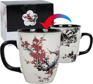Two 16oz color changing heat sensitive magic porcelain mugs with black handles feature a red and black cherry blossom design, shown beside their matching box.
