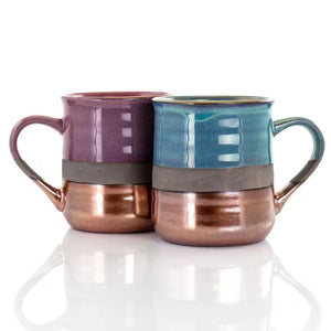 The 18 oz. Assorted Stoneware Mug set includes four sleek, modern mugs with large handles, each featuring a copper bottom and colorful upper half designs in purple, teal, and more.
