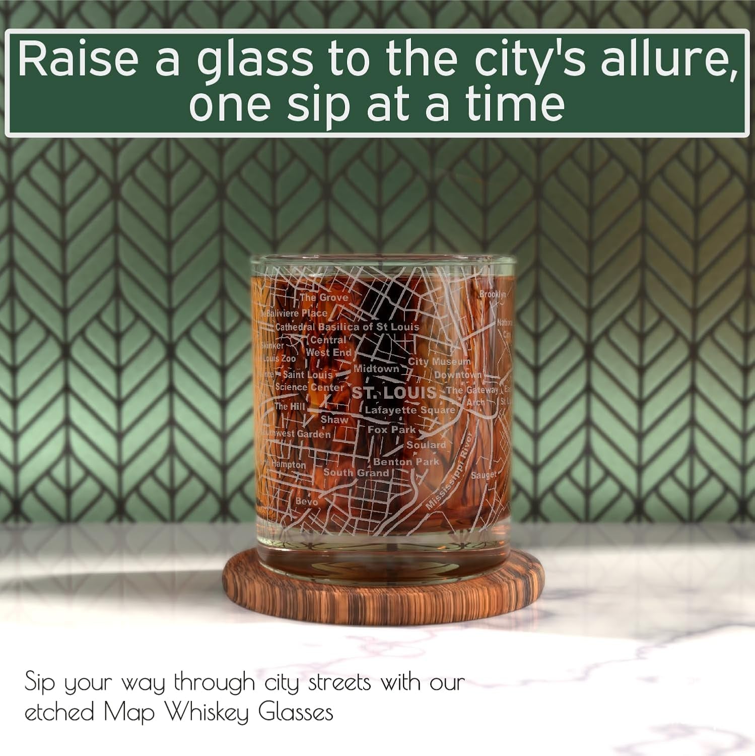 A set of two 10 oz whiskey glasses for St. Louis lovers features a detailed city map design and rests on a wooden coaster against a green patterned background.