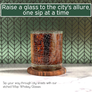 A set of two 10 oz whiskey glasses for St. Louis lovers features a detailed city map design and rests on a wooden coaster against a green patterned background.