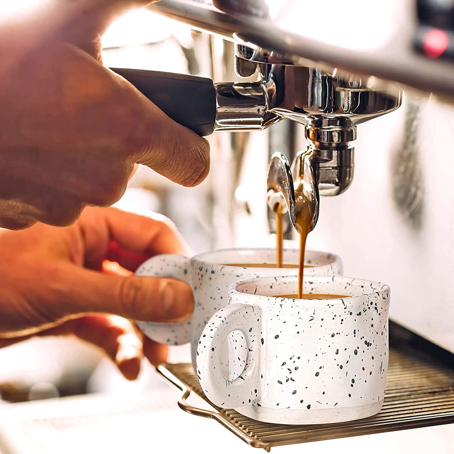 A person brews two espresso shots into Ceramic Coffee Mugs, Stoneware Coffee Cups, Set Of 4, 10oz, placed on the espresso machine's drip tray.