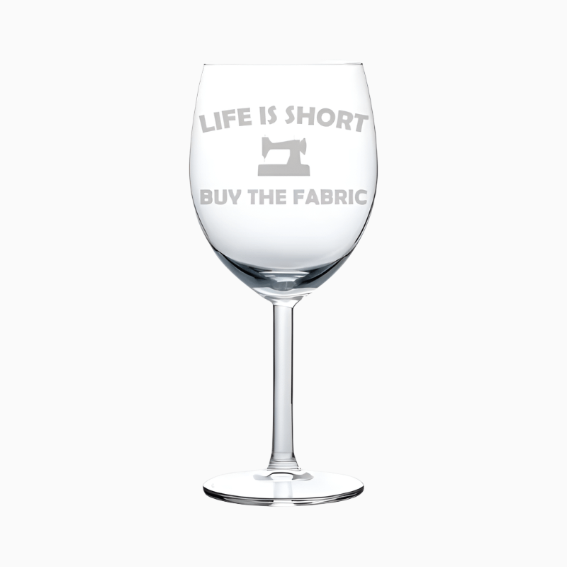 The Wine Glass Goblet Life Is Short Buy The Fabric (10 oz) features a sewing machine and slogan—perfect as a funny sewing wine glass or gift for any seamstress or quilter.