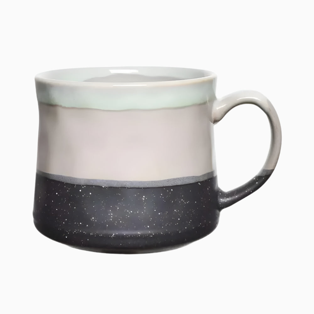 The Large Ceramic Coffee Mug 21 Oz, Grey features a curved handle, light gray top, dark speckled bottom with glossy glaze. Dishwasher and microwave safe for daily use.