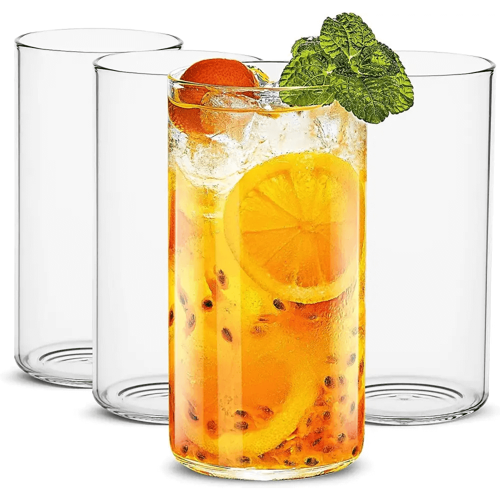 Four stylish Thin Highball Glasses (19 oz) are shown, with one in front filled with an iced citrus drink, garnished with mint, orange, and passion fruit—an elegant set ideal for serving refreshing beverages.