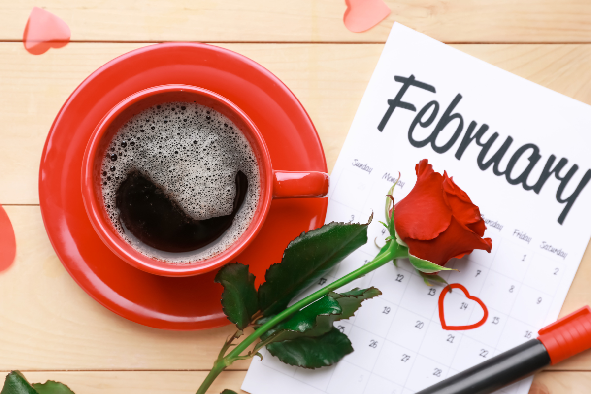 Image of calendar showing the month of February covered by a rose and a red coffee mug of to the left side 