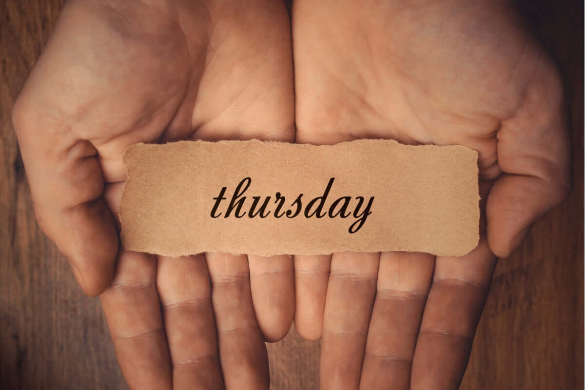 Image of a palm with a brown paper. written on it "thursday"."