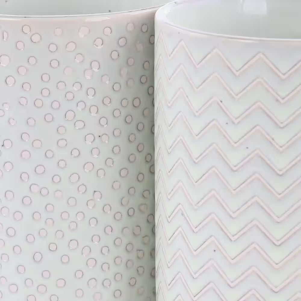 The Madrina 4 Piece 19 oz. Stoneware Mug Set in Mint features assorted designs, including polka dots and chevron, with two stylish white mugs placed side by side.