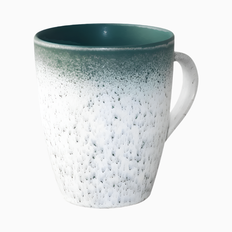 The Macchiaco 18 Oz Catania Home Ceramic Coffee Mug features a curved handle, smooth glossy interior, and a speckled white to dark green reactive glaze gradient. It is displayed against a plain white background.