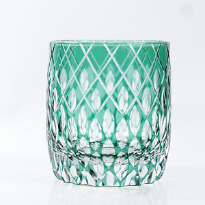 The Macchiaco Fashion Hand Carved Crystal Glass Cup features a short, round design with a green tint and diamond-cut pattern, blending modern simplicity. Displayed against a plain white background.