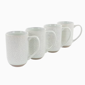 The Madrina 4 Piece 19 oz. Stoneware Assorted Designs Beverage Mug Set in Mint features four microwave-safe mugs with handles, assorted embossed patterns including florals, and slightly exposed brown bases, all arranged in a row.