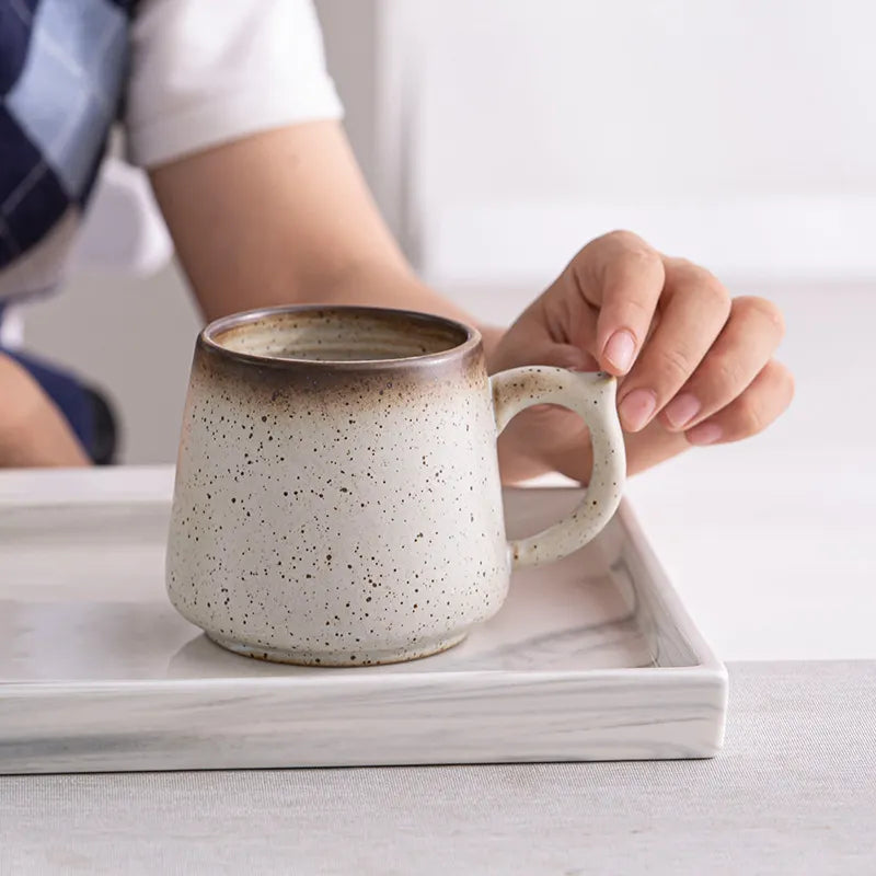 a hand touching macchiaco's cocoa coffee mug